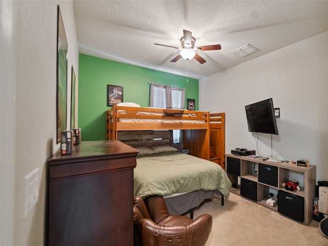 bedroom with a textured ceiling, a ceiling fan, visible vents, and carpet floors