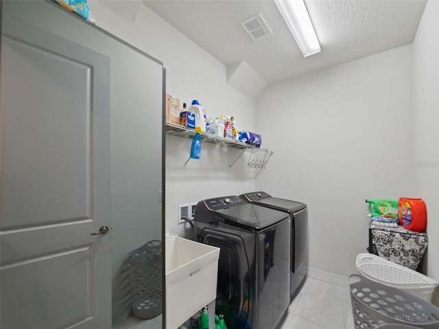 clothes washing area with laundry area, light tile patterned floors, separate washer and dryer, visible vents, and a sink