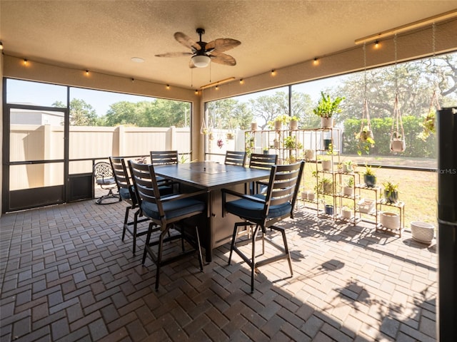 sunroom / solarium with a ceiling fan and outdoor dining area
