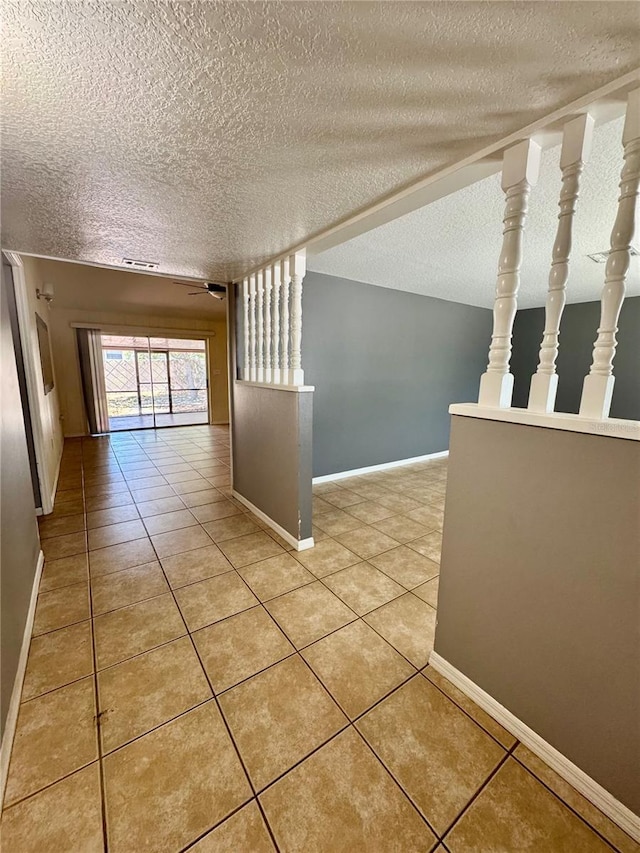 corridor featuring a textured ceiling, light tile patterned floors, and baseboards