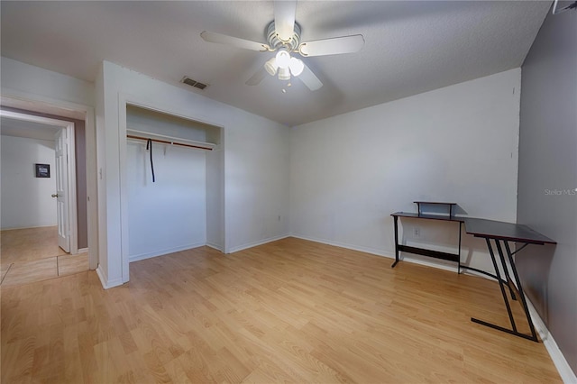 unfurnished bedroom featuring light wood-style floors, a closet, baseboards, and a ceiling fan