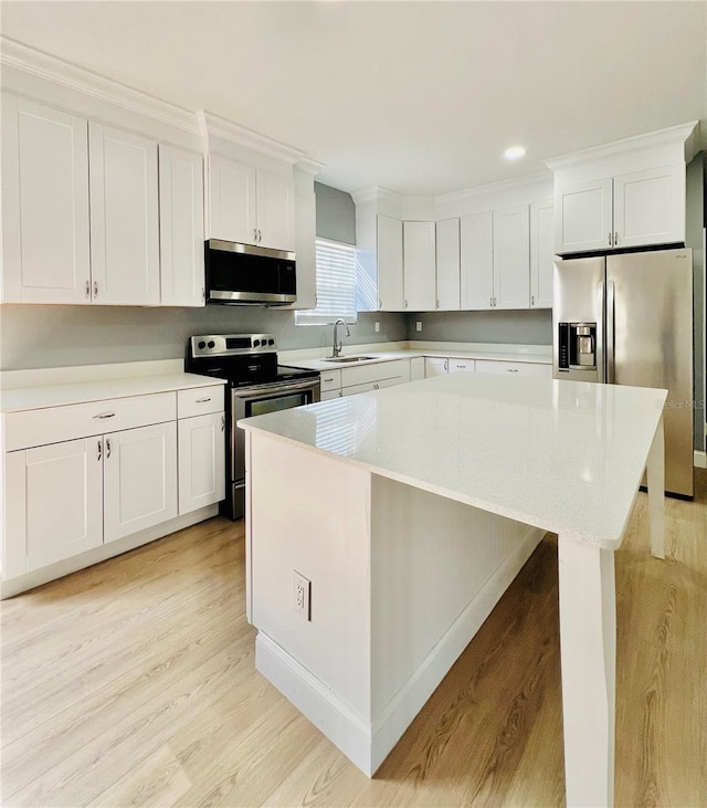 1002 E N Bay St, Tampa, FL 33603 - kitchen with appliances with stainless steel finishes, light wood-style floors, white cabinetry, and a center island