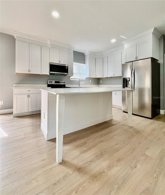 1002 E N Bay St, Tampa, FL 33603 - kitchen featuring appliances with stainless steel finishes, light countertops, light wood-style flooring, white cabinets, and a center island