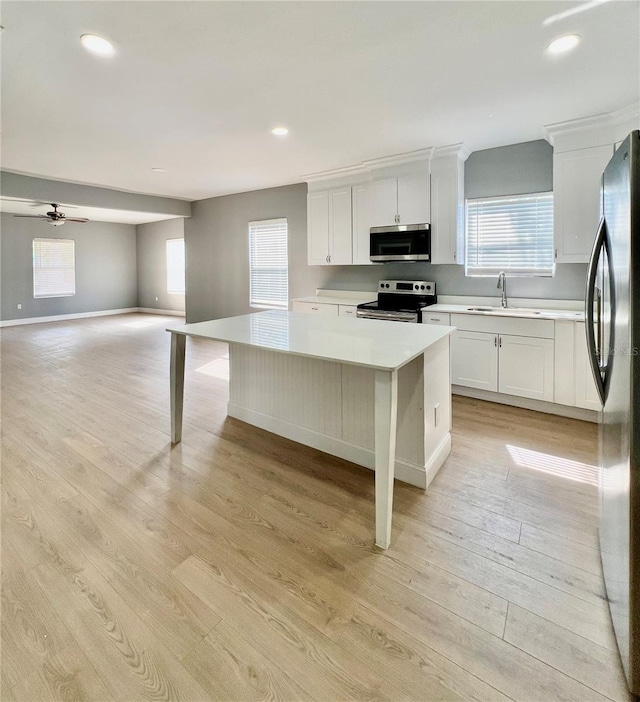 1002 E N Bay St, Tampa, FL 33603 - kitchen featuring appliances with stainless steel finishes, light countertops, light wood finished floors, a sink, and white cabinetry