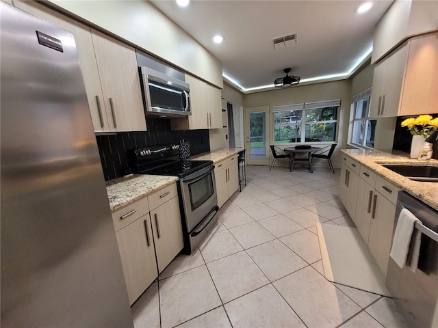 824 Greenbelt Cir, Brandon, FL 33510 - kitchen with stainless steel appliances, decorative backsplash, light tile patterned flooring, recessed lighting, and light stone counters