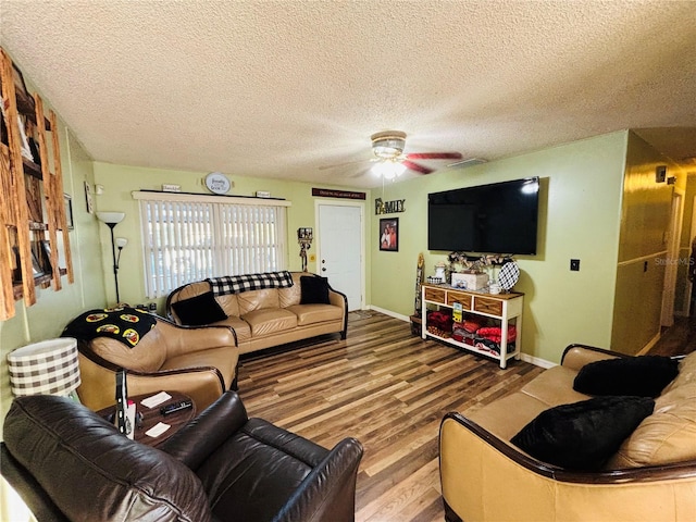 living area featuring a textured ceiling, wood finished floors, baseboards, and a ceiling fan