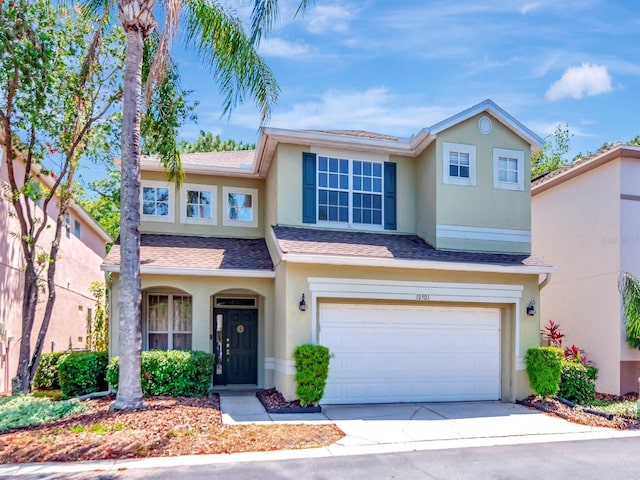 traditional home with an attached garage, driveway, and stucco siding