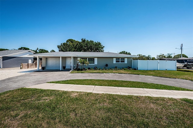 ranch-style house featuring a front lawn, fence, a garage, and driveway