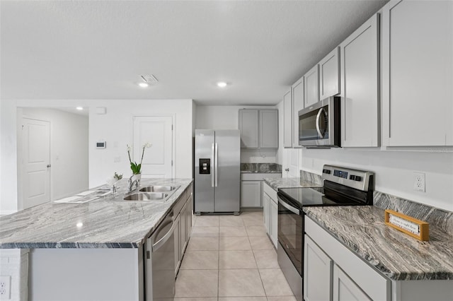 7530 Broad Pointe Dr, Zephyrhills, FL 33540 - kitchen featuring stainless steel appliances, light tile patterned flooring, an island with sink, light stone countertops, and recessed lighting