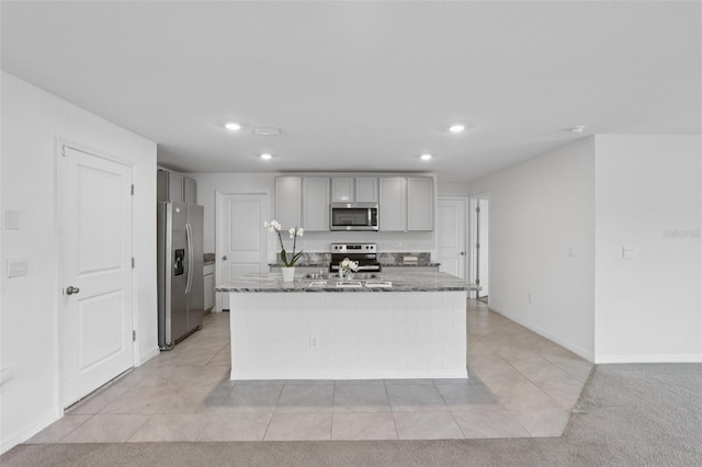 7530 Broad Pointe Dr, Zephyrhills, FL 33540 - kitchen with stainless steel appliances, dark stone countertops, recessed lighting, gray cabinets, and a kitchen island with sink