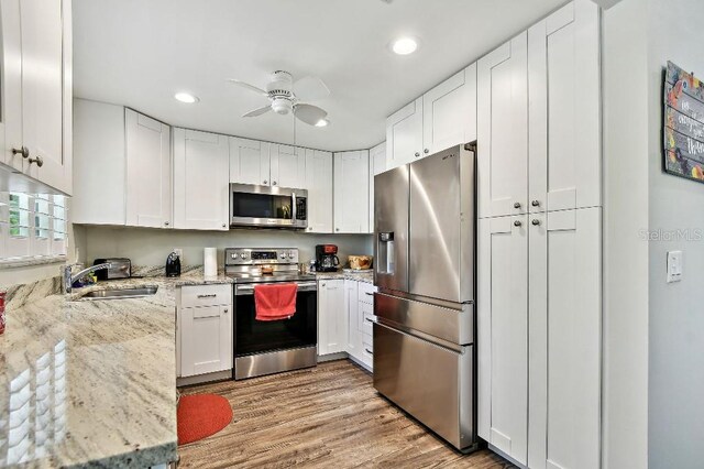 2291 Americus Blvd W Unit 41, Clearwater, FL 33763 - kitchen featuring white cabinetry, a ceiling fan, appliances with stainless steel finishes, light wood finished floors, and a sink