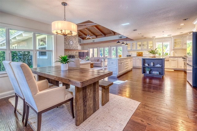 dining area with an inviting chandelier, lofted ceiling, a textured ceiling, and dark wood-type flooring
