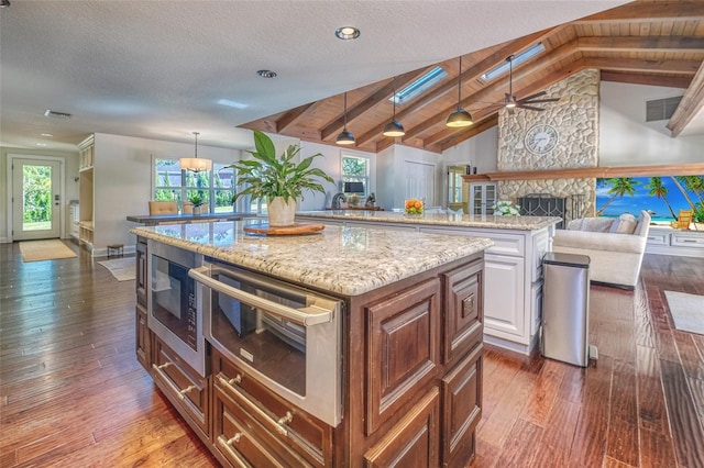 kitchen with dark wood-type flooring, built in microwave, and a kitchen island