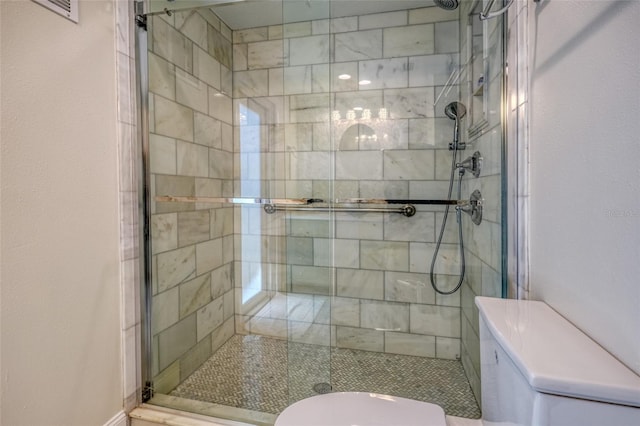 full bathroom with a shower stall, toilet, and visible vents