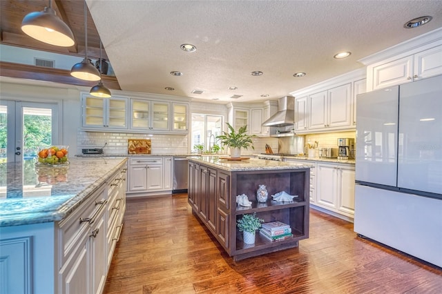 898 Cypress Lakeview Ct, Tarpon Springs, FL 34688 - kitchen with freestanding refrigerator, a kitchen island, stainless steel dishwasher, white cabinets, and wall chimney range hood