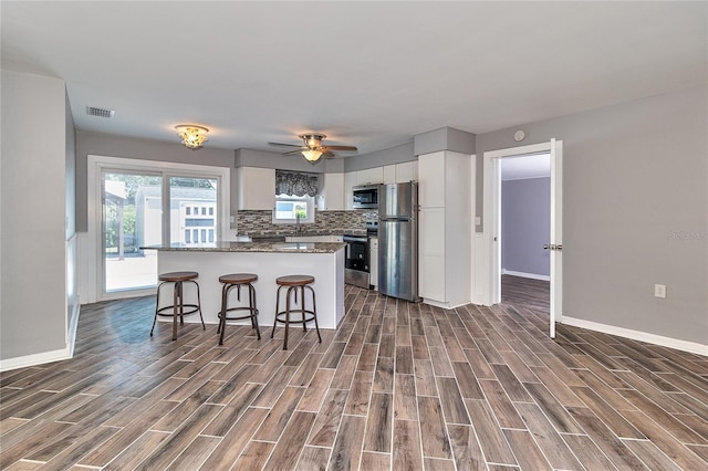 3045 Stratford Dr, Largo, FL 33771 - kitchen with white cabinets, a kitchen bar, appliances with stainless steel finishes, and dark wood finished floors