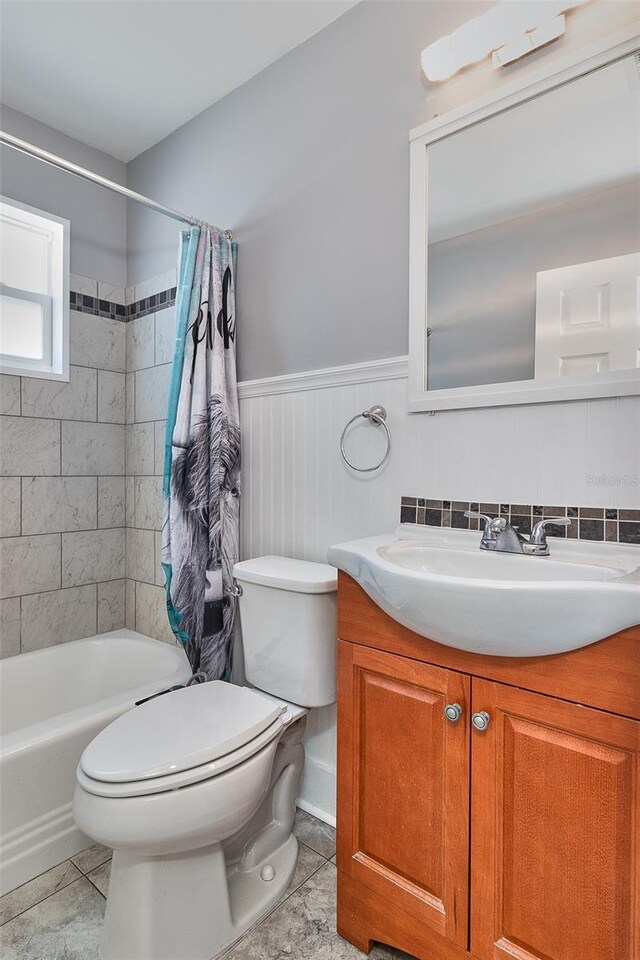3045 Stratford Dr, Largo, FL 33771 - full bath with wainscoting, vanity, shower / bath combination with curtain, toilet, and tile patterned flooring