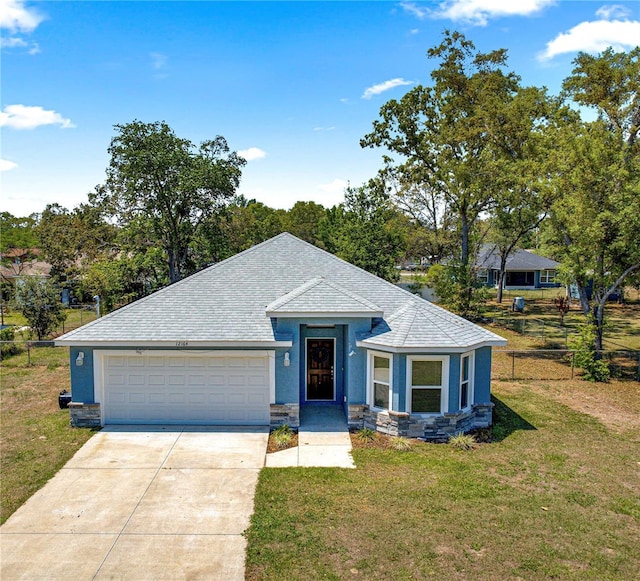 ranch-style home with a garage, stucco siding, roof with shingles, a front yard, and concrete driveway