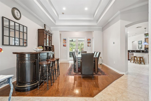 15930 Sorawater Dr, Lithia, FL 33547 - dining room featuring arched walkways, a dry bar, a tray ceiling, wood finished floors, and baseboards