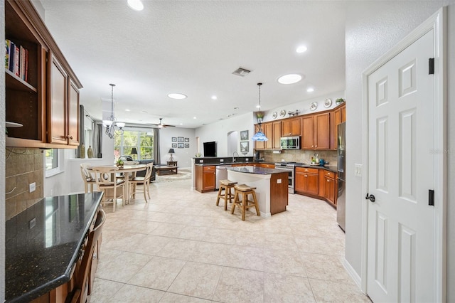 15930 Sorawater Dr, Lithia, FL 33547 - kitchen with appliances with stainless steel finishes, decorative backsplash, brown cabinetry, hanging light fixtures, and recessed lighting