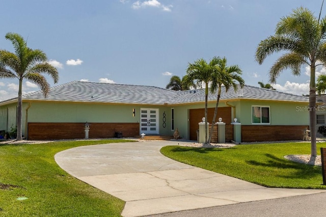 600 Eleuthera Dr, Punta Gorda, FL 33950 - ranch-style house featuring stucco siding, curved driveway, french doors, a front lawn, and an attached garage