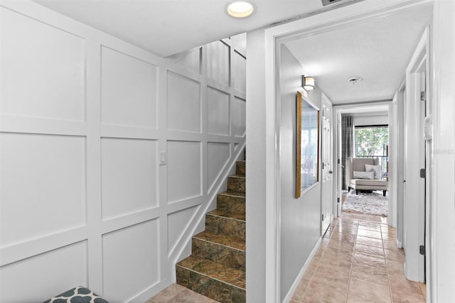 105 4th Ave NE Unit 219, Saint Petersburg, FL 33701 - hallway featuring baseboards, a decorative wall, and stairway