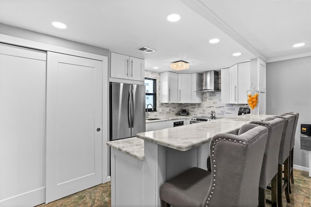 105 4th Ave NE Unit 219, Saint Petersburg, FL 33701 - kitchen featuring freestanding refrigerator, a peninsula, a breakfast bar, recessed lighting, and wall chimney exhaust hood