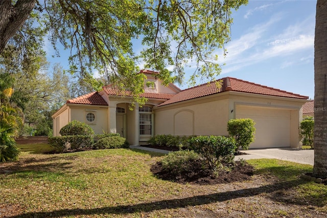 mediterranean / spanish house with a tiled roof, a garage, stucco siding, and concrete driveway