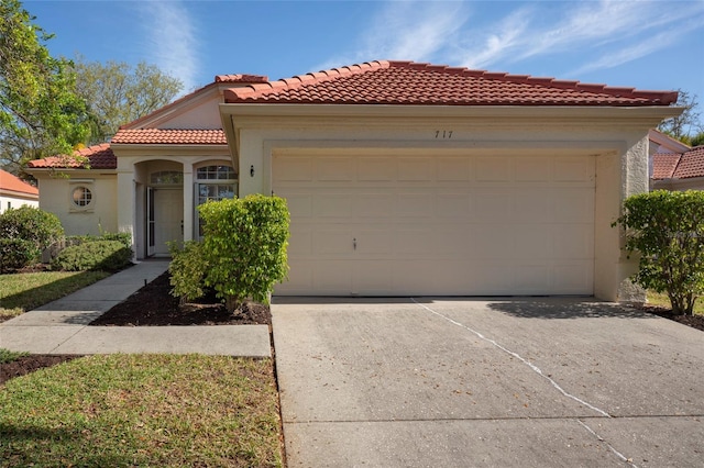 mediterranean / spanish house featuring a tiled roof, stucco siding, a garage, and concrete driveway