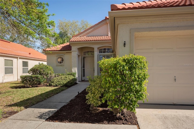 view of front facade featuring stucco siding, a tiled roof, and an attached garage