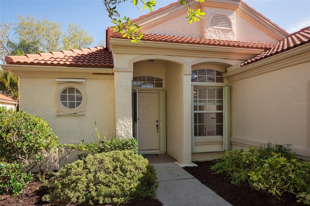 doorway to property with a tiled roof and stucco siding