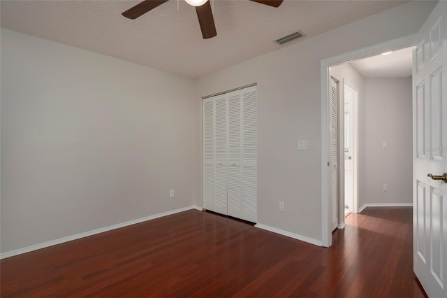 unfurnished bedroom with ceiling fan, a closet, visible vents, hardwood / wood-style floors, and baseboards