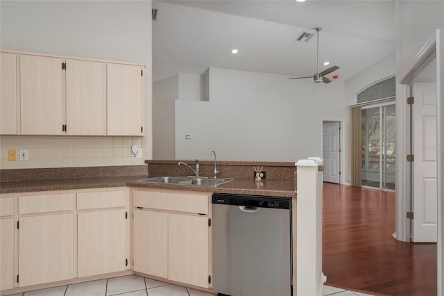 kitchen featuring vaulted ceiling, a peninsula, backsplash, stainless steel dishwasher, and a sink