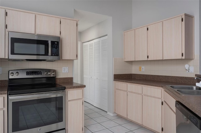 kitchen with a sink, backsplash, appliances with stainless steel finishes, and light brown cabinetry