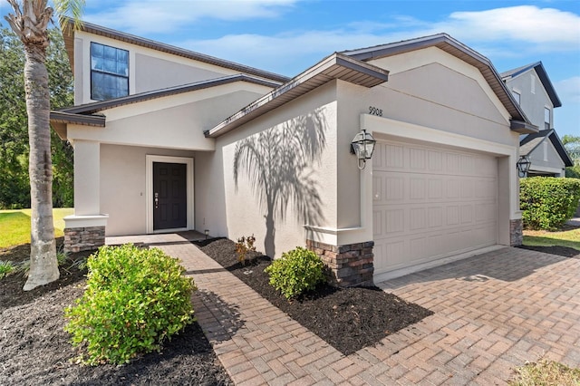 view of front of home featuring driveway, stone siding, a garage, and stucco siding
