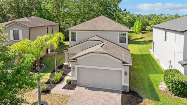 traditional-style home with a front yard, a shingled roof, a garage, stucco siding, and decorative driveway