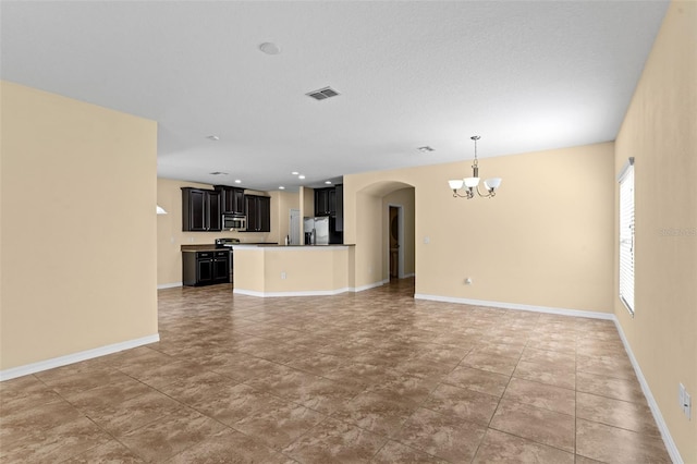 unfurnished living room featuring arched walkways, an inviting chandelier, baseboards, and visible vents