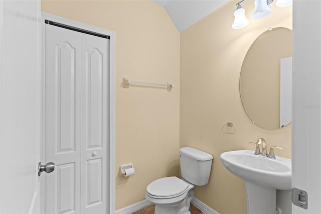 bathroom with toilet, a sink, baseboards, and vaulted ceiling