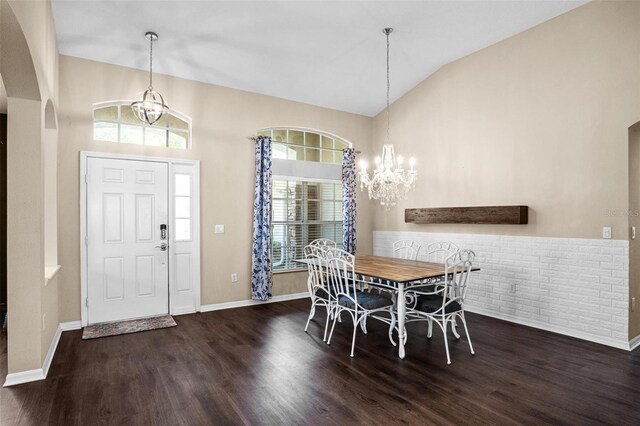 dining space featuring high vaulted ceiling, arched walkways, an inviting chandelier, and wood finished floors