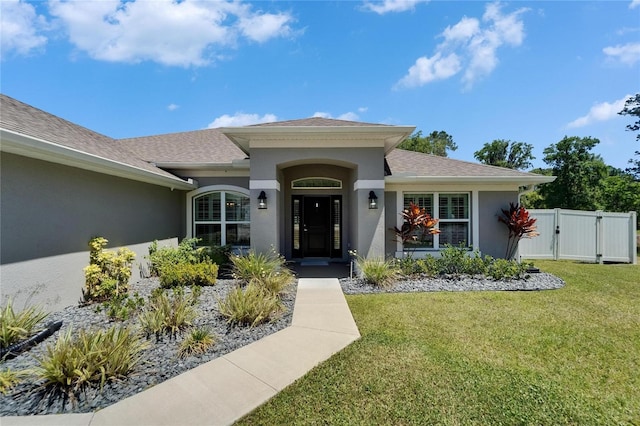 5419 Knights Landing Dr, Lakeland, FL 33810 - doorway to property with stucco siding, a lawn, roof with shingles, fence, and a gate