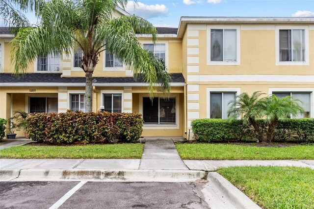 townhome / multi-family property with stucco siding and uncovered parking