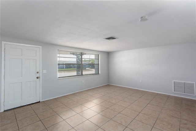 empty room featuring visible vents, baseboards, and light tile patterned flooring