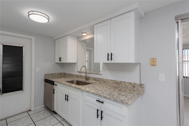 kitchen featuring stainless steel dishwasher, light stone countertops, white cabinetry, a sink, and baseboards