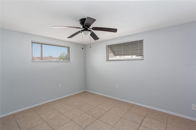 empty room featuring light tile patterned flooring, ceiling fan, and baseboards