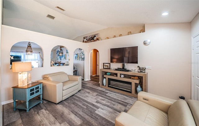 living room with baseboards, vaulted ceiling, visible vents, arched walkways, and wood finished floors
