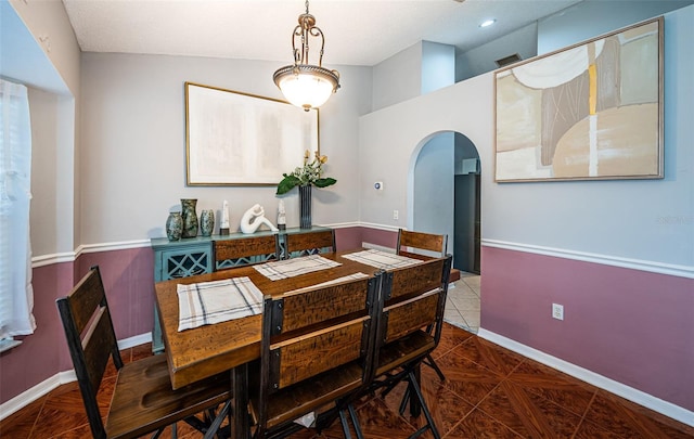 dining room featuring arched walkways and baseboards
