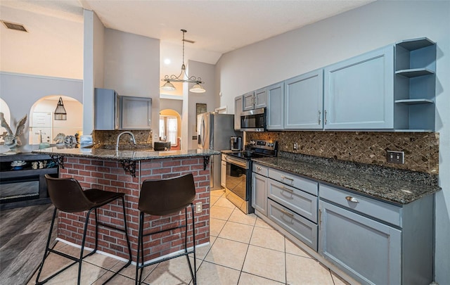 kitchen featuring visible vents, open shelves, appliances with stainless steel finishes, a peninsula, and a kitchen bar