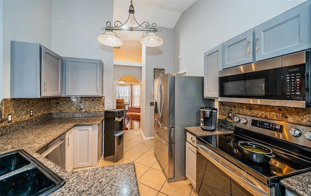 kitchen featuring light tile patterned flooring, dark stone countertops, decorative backsplash, and stainless steel appliances