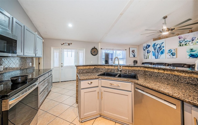 kitchen with tasteful backsplash, light tile patterned floors, dark stone countertops, a sink, and appliances with stainless steel finishes