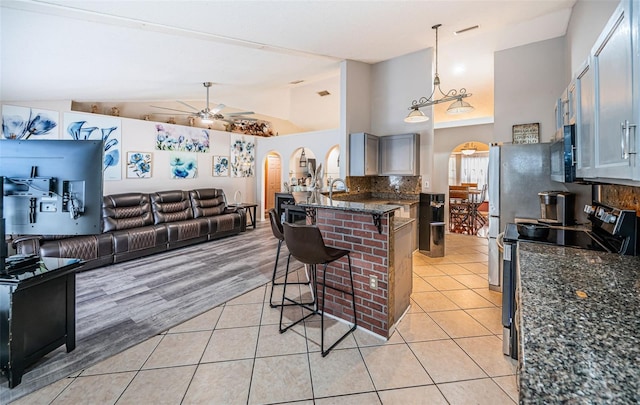 kitchen with black microwave, a kitchen bar, electric range, a ceiling fan, and open floor plan